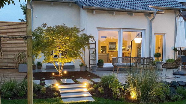 Modern outdoor lighting with warm white LED spots and floor lamp in garden by house terrace.