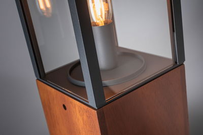 Close-up of modern table lamp with wooden base and black metal frame featuring a glowing bulb