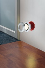 Recessed LED floor spotlight with stainless steel ring and red housing mounted on wall near wooden floor