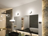 Modernes Badezimmer mit schwarzen Armaturen, schwarzem Waschbecken und runden Wandlampen in Weiß und Schwarz.