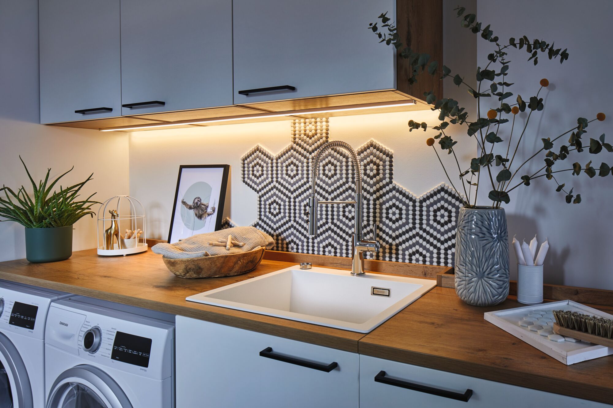 Cuisine moderne avec évier blanc, plan de travail en bois et crédence en mosaïque hexagonale éclairée par LED