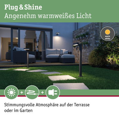 Moderne schwarze LED-Gartenleuchten mit warmweißem Licht auf Rasenweg vor Terrasse mit Sitzmöbeln