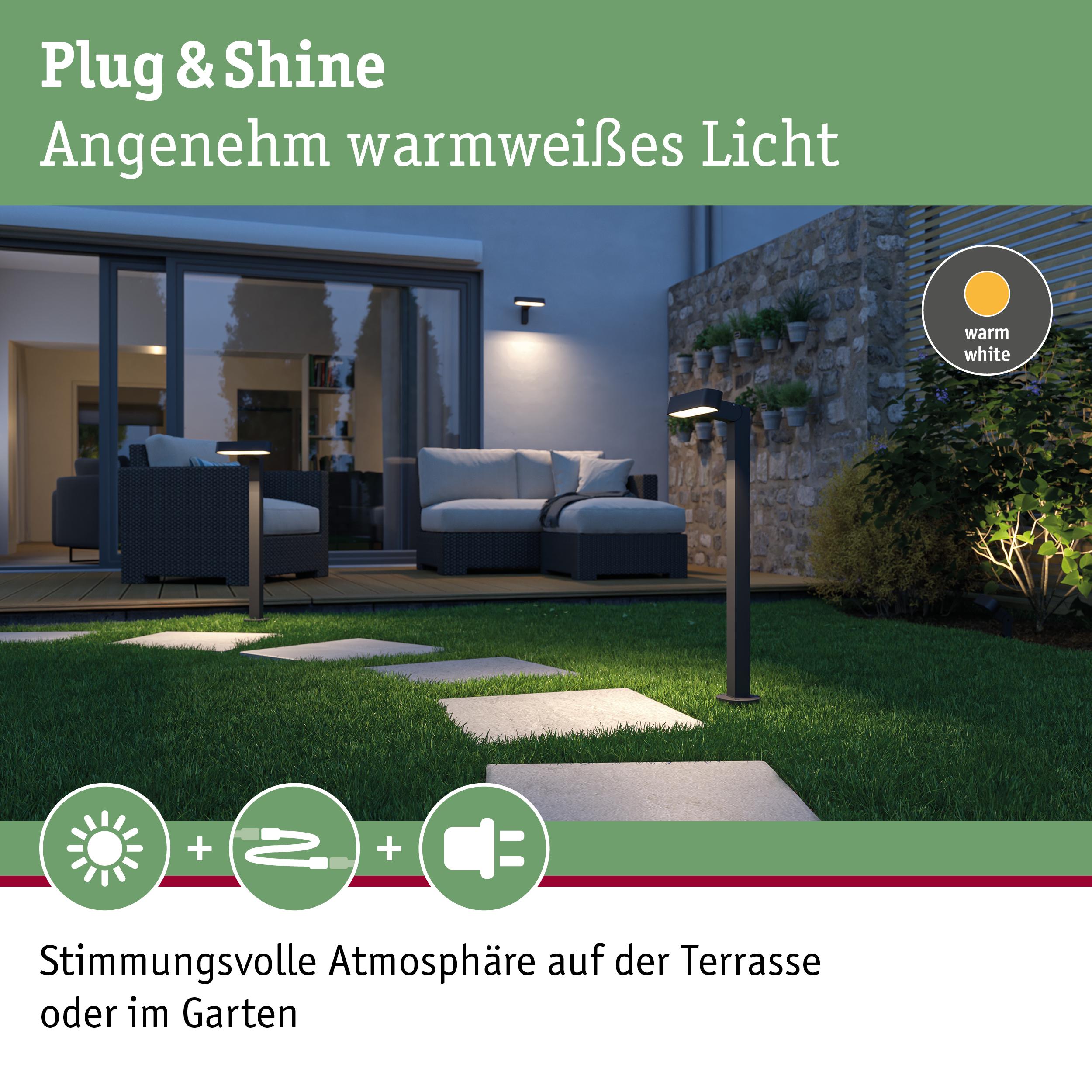 Moderne schwarze LED-Gartenleuchten mit warmweißem Licht auf Rasenweg vor Terrasse mit Sitzmöbeln