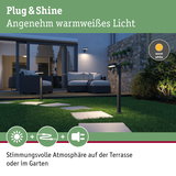 Moderne schwarze LED-Gartenleuchten mit warmweißem Licht auf Rasenweg vor Terrasse mit Sitzmöbeln