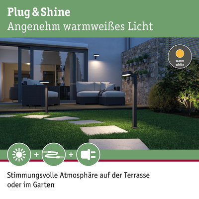 Moderne schwarze LED-Gartenleuchten mit warmweißem Licht auf Rasenweg vor Terrasse mit Sitzmöbeln