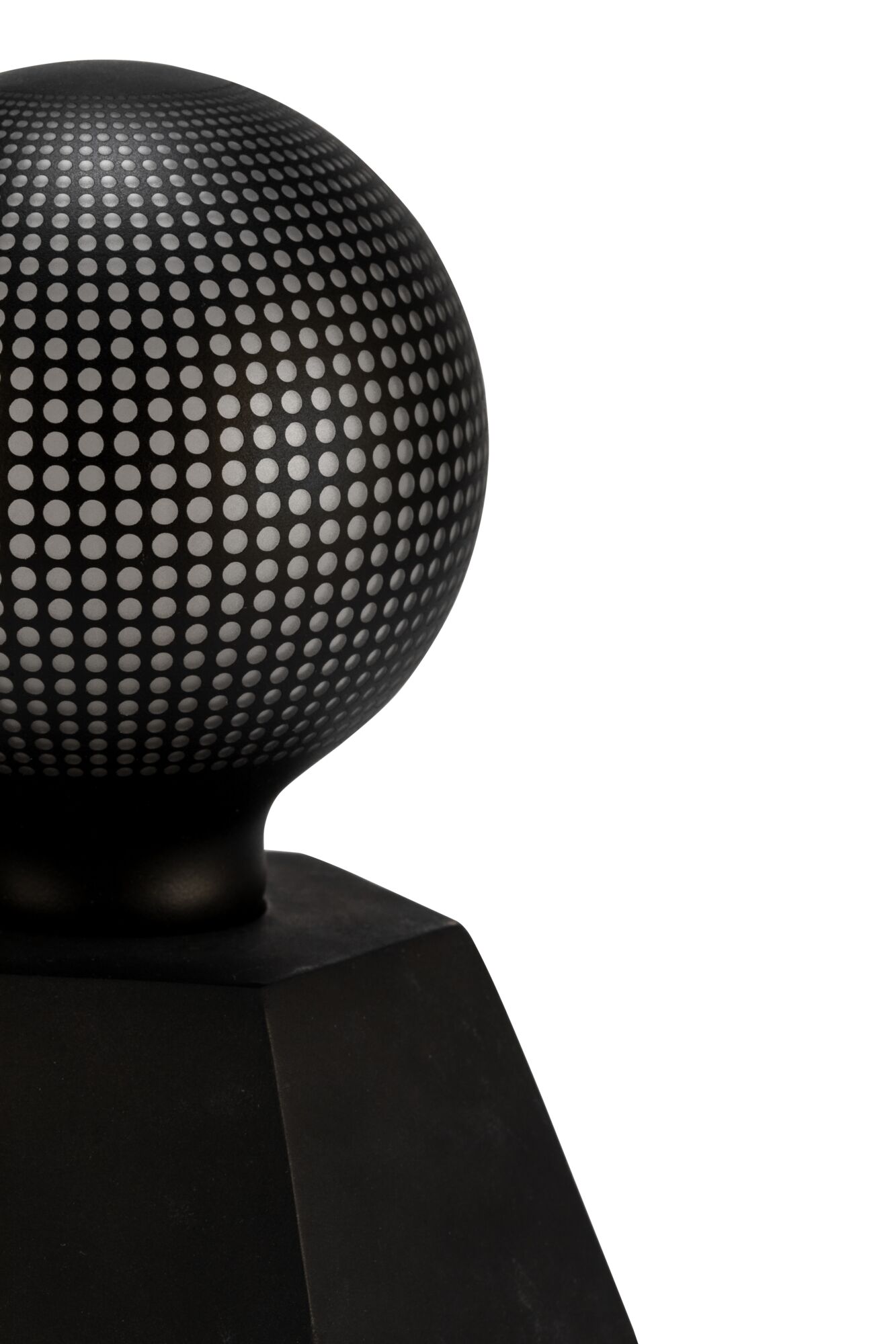 Black metal sphere with perforated pattern on square base, modern decorative object