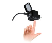 Black power adapter with protective cover and cable, finger pressing white switch for light control