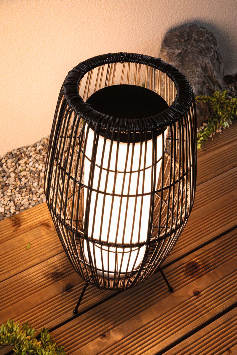 Moderne schwarze Metalllaterne mit weißem Leuchtmittel auf Holzterrasse für Außenbeleuchtung.
