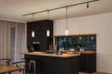 Modern kitchen with black wood cabinets and wooden countertop, three white pendant lights on black track lighting.