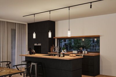 Moderne køkken med sorte træskabe og træbordplade, tre hvide pendellamper på sort skinne.