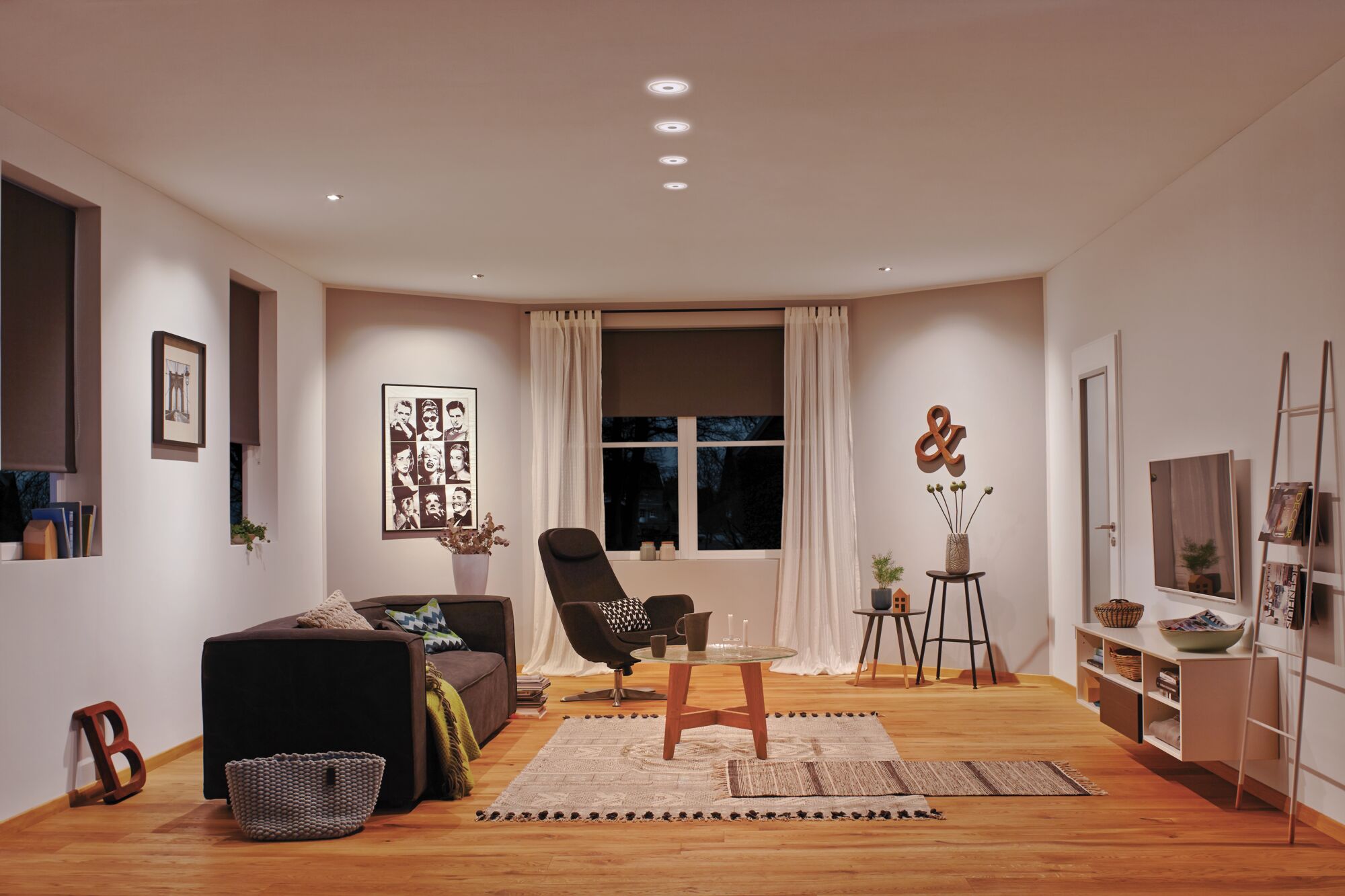 Modern living room with wooden floor, black armchair, sofa, and warm white LED ceiling lights.