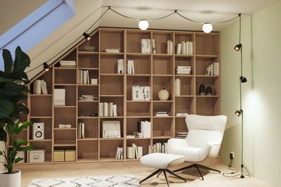 Modern green cable light strip with black spotlights and white globes in cozy reading room with wooden shelves