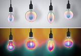 Vier bunte LED-Glühbirnen mit schwarzem Sockel an weißer und bunter Wand für dekorative Beleuchtung