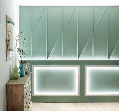 Groene muur met LED-verlichting in rechthoekige lijsten en houten kast met vazen in moderne woonruimte