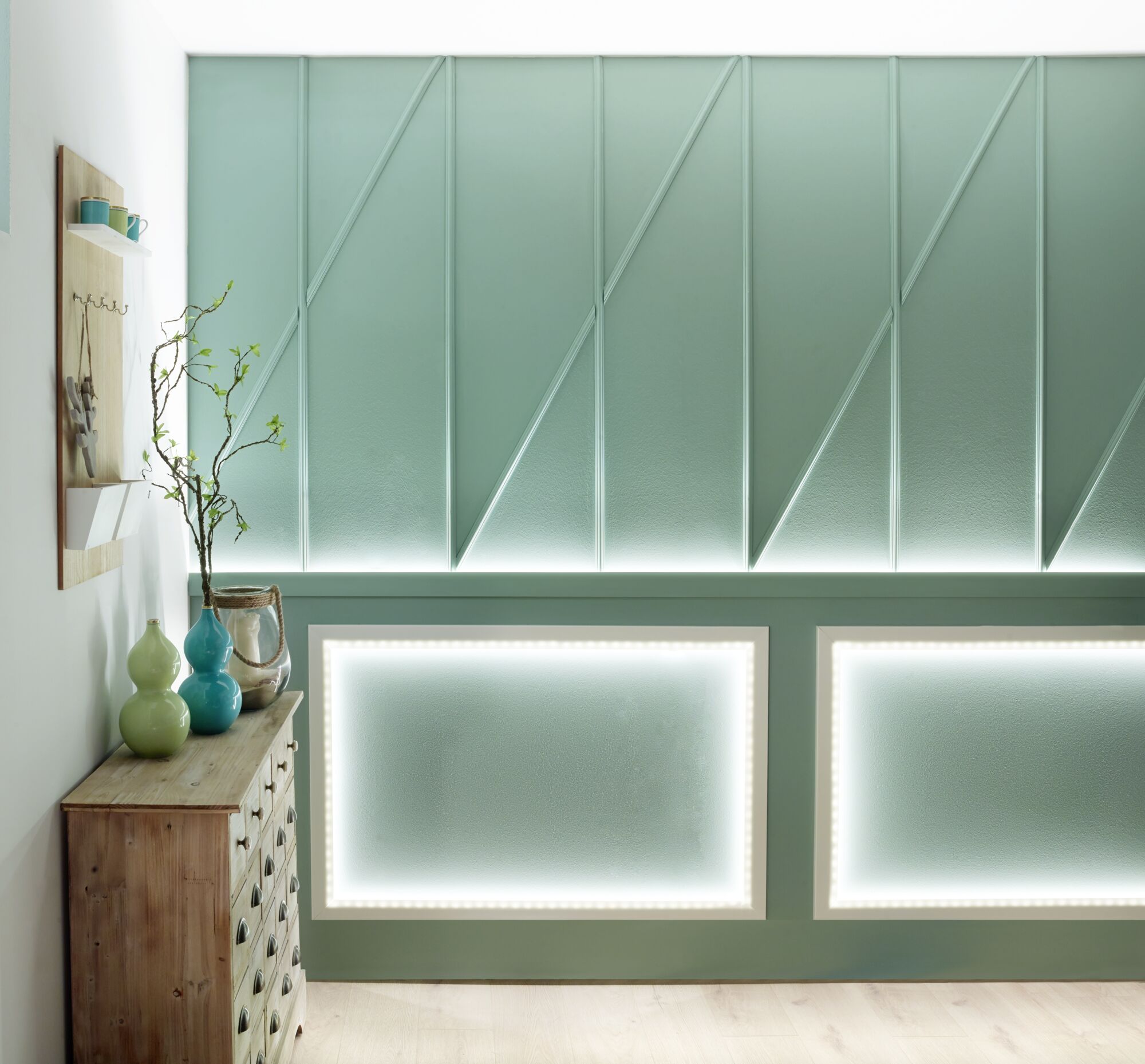 Mur vert avec éclairage LED en cadres rectangulaires et meuble en bois avec vases dans un espace moderne