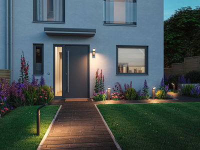 Moderne Außenbeleuchtung mit schwarzen LED-Wegeleuchten und Wandlampen an Haus mit Gartenweg und Blumen.