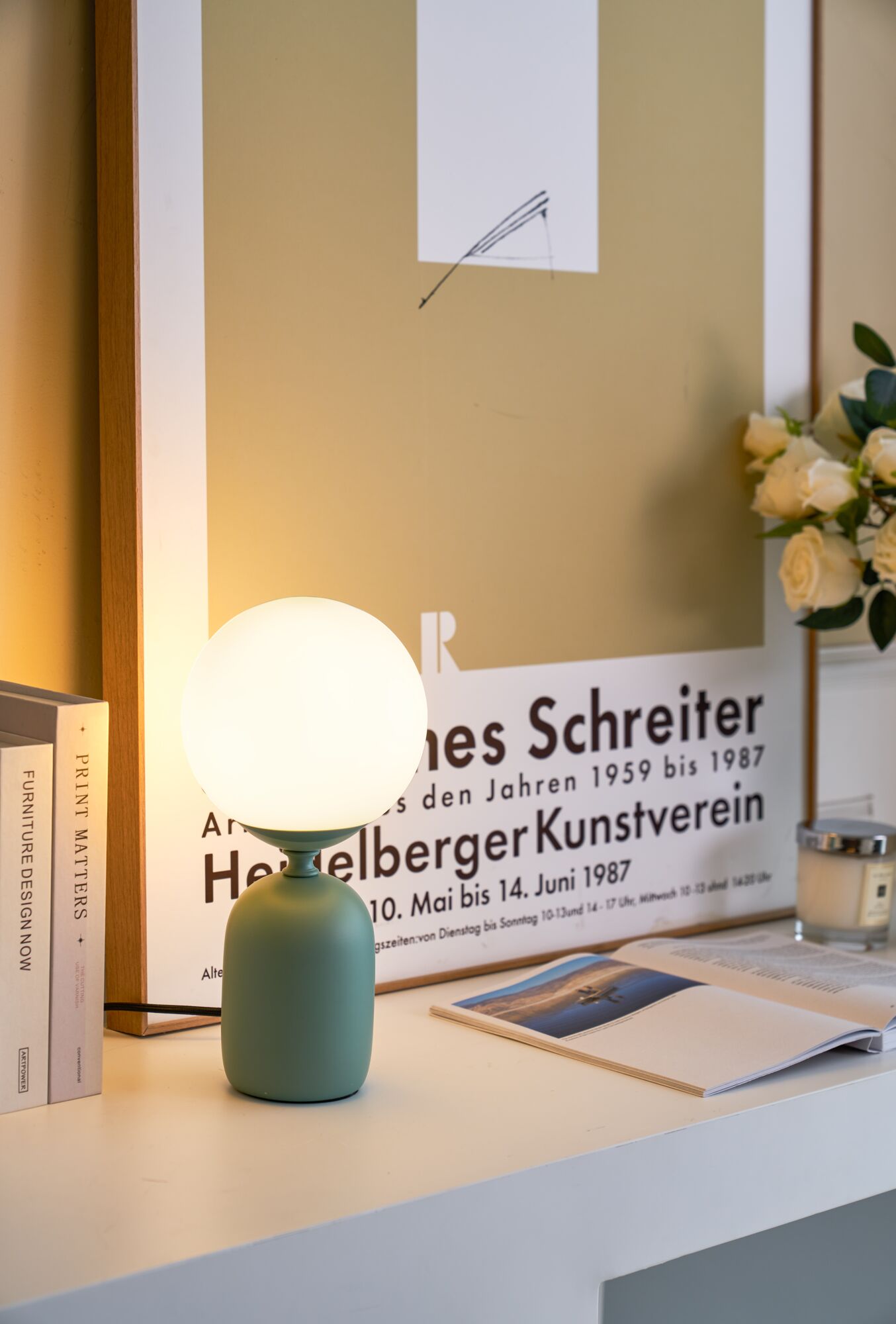 Moderne Tischlampe mit grünem Metallfuß und rundem weißem Glaslicht für stimmungsvolle Beleuchtung.