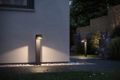 Moderne schwarze LED-Außenleuchte aus Metall beleuchtet Gartenweg mit warmweißem Licht.