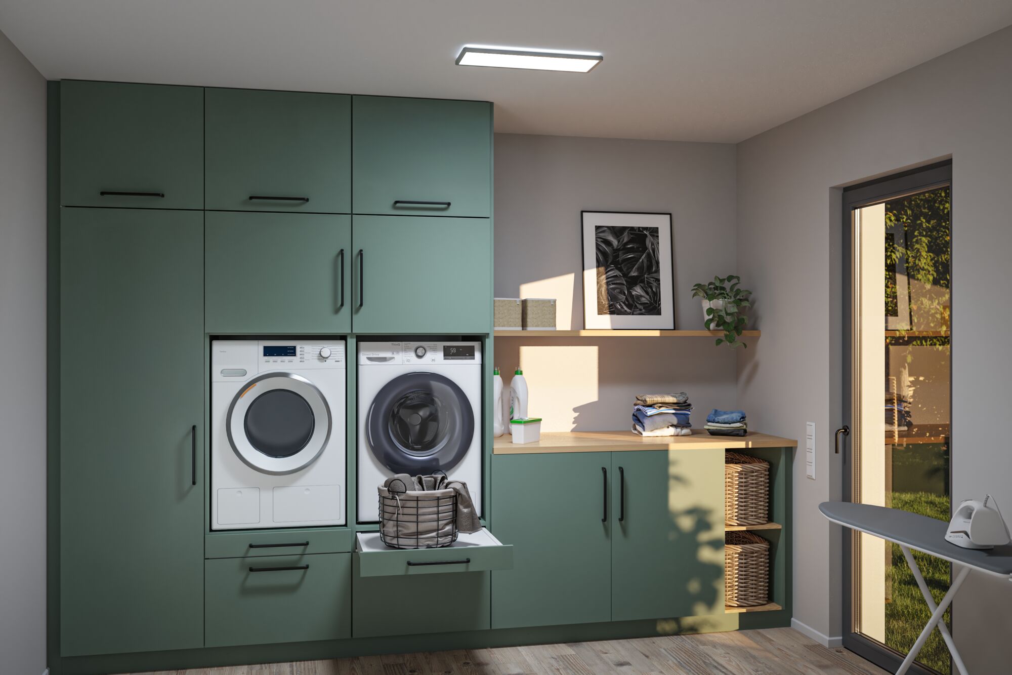 Buanderie moderne en bois vert avec machine à laver, sèche-linge, panier à linge et planche à repasser à la lumière du jour