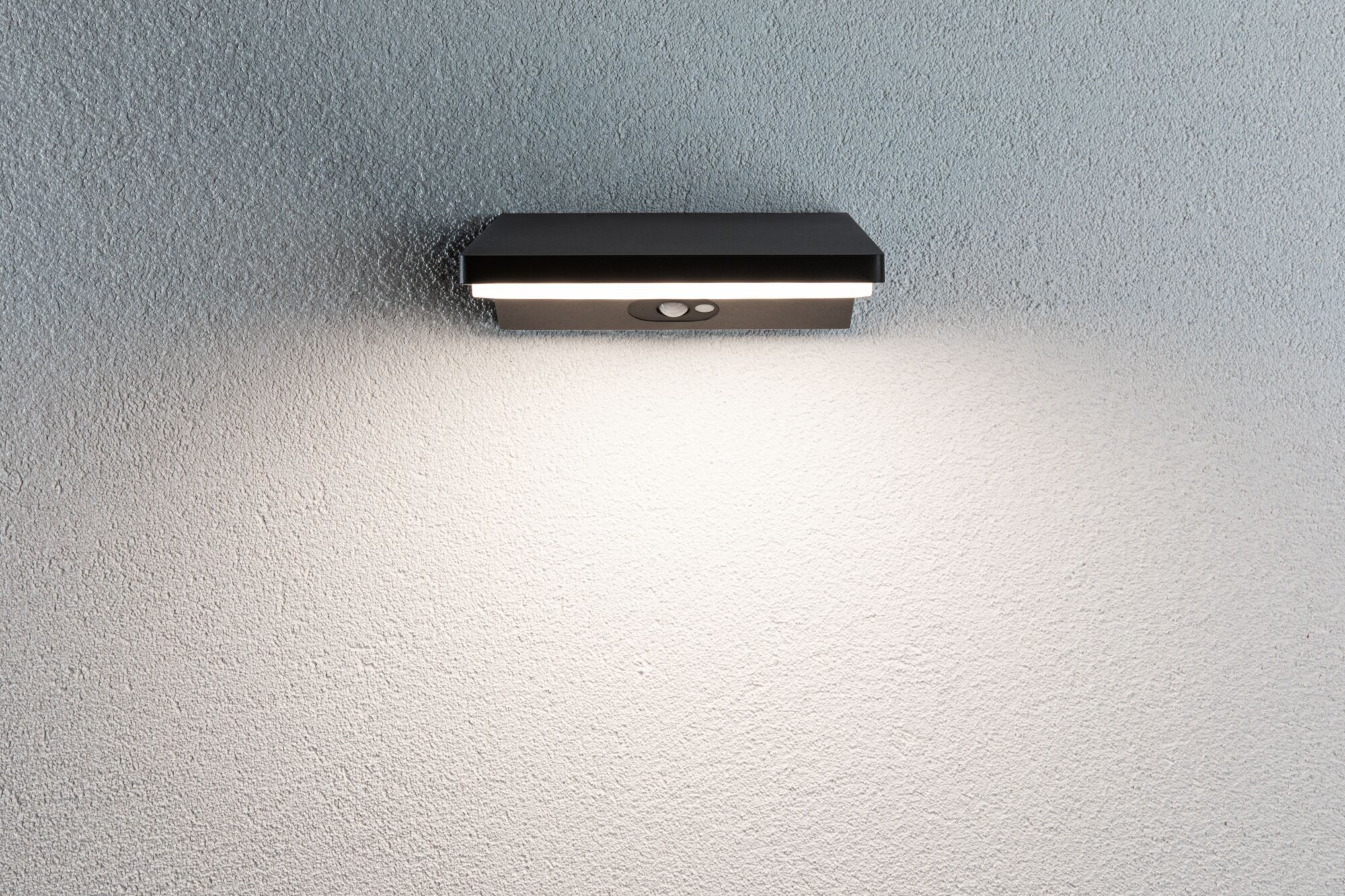 Black metal LED wall light with motion sensor mounted on white wall for outdoor lighting