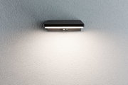 Schwarze LED-Wandleuchte aus Metall mit Bewegungsmelder an strukturierter grauer Wand für Außenbeleuchtung