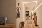 Couloir moderne avec bande LED MaxLED Flow blanc chaud, sol en bois et décoration minimaliste