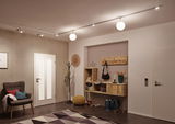 Moderne hal met houten plank, grijze fauteuil, gele poef en plafondlamp met witte bollen