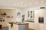 Modern white country kitchen with wooden countertop and integrated stainless steel oven lighting