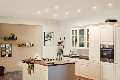 Moderne witte landelijke keuken met houten werkblad en geïntegreerde roestvrijstalen ovenverlichting