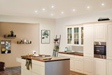Modern white country kitchen with wooden countertop and integrated stainless steel oven lighting