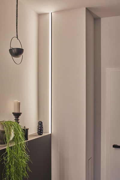 Slim LED light strip in wall niche with warm white light, modern interior lighting design.