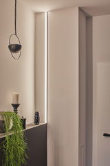 Slim LED light strip in wall niche with warm white light, modern interior lighting design.