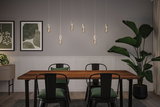 Modern dining area with wooden table, black metal chairs, and six hanging LED bulbs emitting warm light.