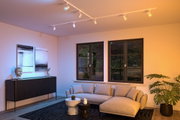Salon moderne avec rails d'éclairage au plafond blancs et lumière blanche chaude pour une ambiance élégante