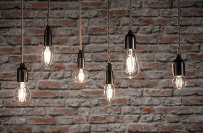 Six ampoules LED filament claires de formes variées suspendues devant un mur en briques rouges pour éclairage décoratif