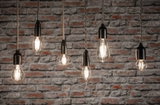 Sechs klare Filament-LED-Leuchtmittel in verschiedenen Formen vor roter Backsteinwand für dekorative Beleuchtung