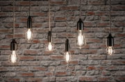 Sechs klare Filament-LED-Leuchtmittel in verschiedenen Formen vor roter Backsteinwand für dekorative Beleuchtung