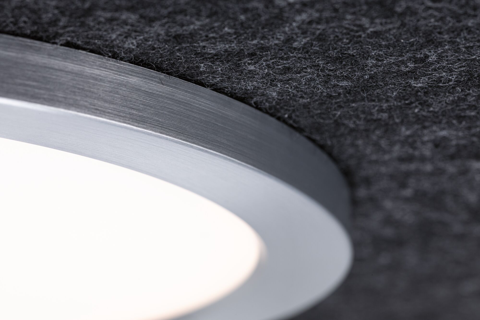 Nahaufnahme einer runden LED-Deckenleuchte mit gebürstetem Aluminiumrand und weißem Diffusor für Wohnräume