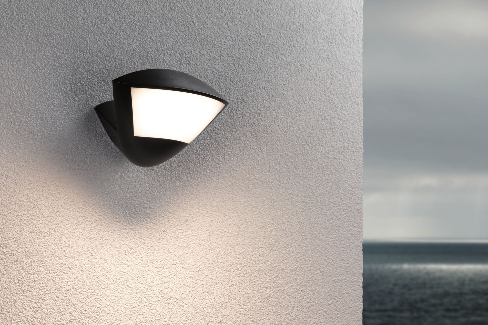 Schwarze Außenwandleuchte mit weißem Diffusor an strukturierter Wand, moderne LED-Außenbeleuchtung