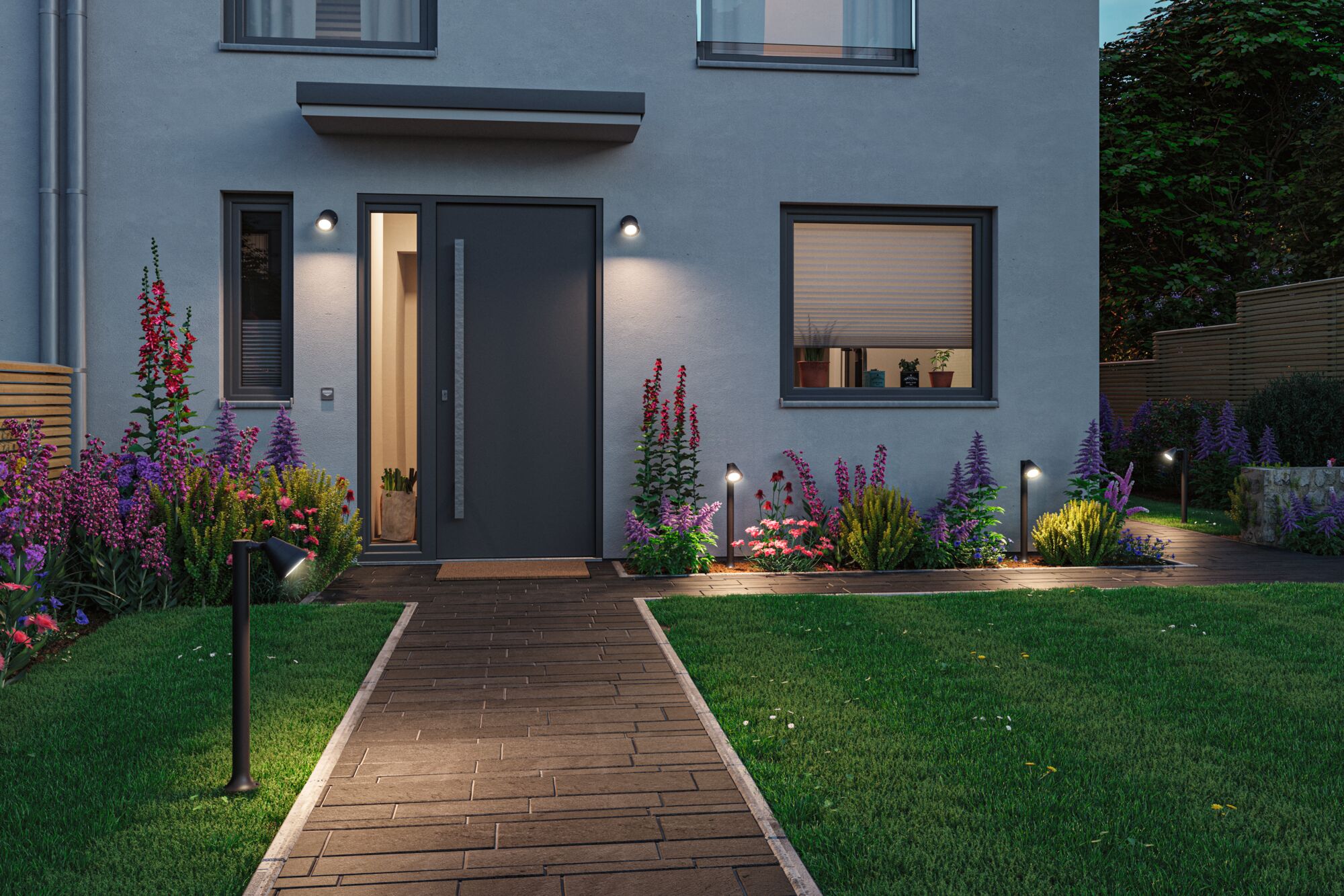 Moderne huisentree met antraciet deurkozijn en warmwitte LED-buitenverlichting langs tuinpad.