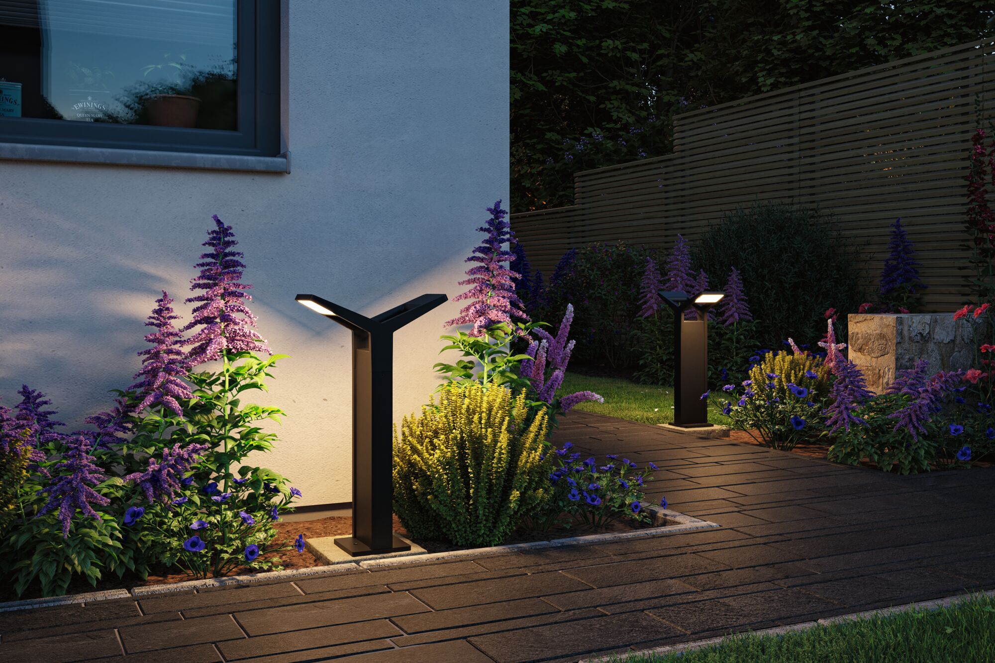 Black metal LED outdoor lights illuminate garden path with purple and blue flowers at dusk