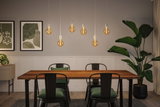 Moderne eetkamer met houten tafel, zwarte metalen stoelen en warme LED-peertjes als hanglampen