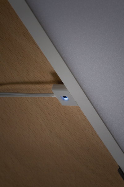 Weißer LED-Schalter mit blauem Licht auf Holzoberfläche für moderne Lichtsteuerung im Innenbereich
