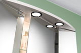 Ensemble de lampes LED rondes à cadre noir sur miroir de salle de bain avec étagère en verre.