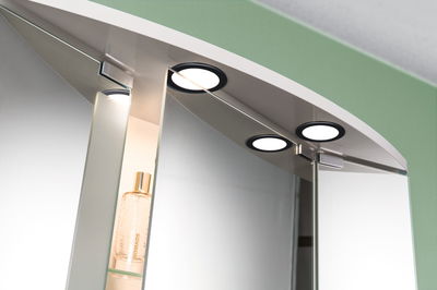 Ensemble de lampes LED rondes à cadre noir sur miroir de salle de bain avec étagère en verre.