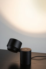 Black metal LED table lamp with round base and adjustable head for focused lighting