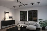Modern living room with black LED track lighting, grey sofa, and black wooden sideboard for interior lighting.