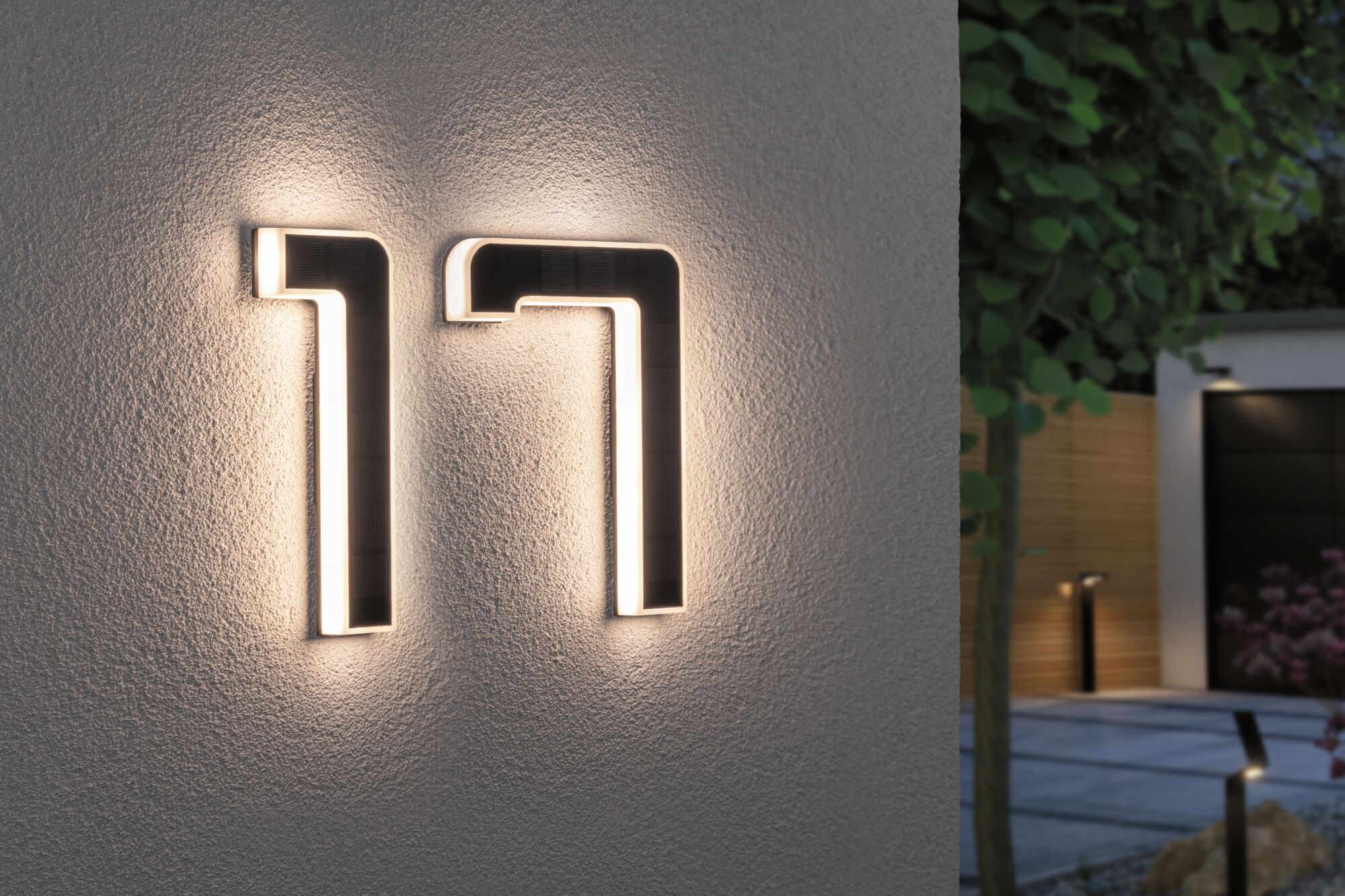 Modern LED house number 17 in black material with warm white light mounted on exterior wall.