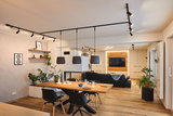 Modern living room with wooden floor, black sofa, wooden dining table and black pendant lights