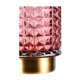 Close-up of pink textured glass lampshade with gold metal base for elegant home lighting